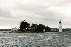 Kleine Insel mit Leuchtturm und Haus unter bewölktem Himmel