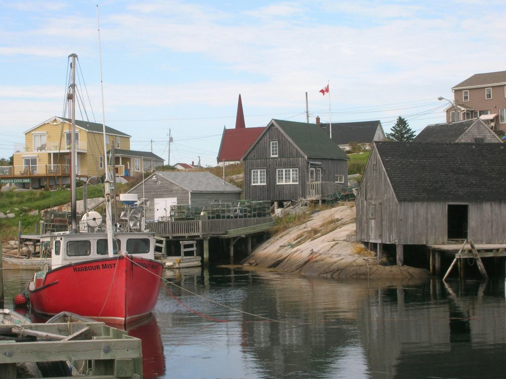 Rotes Fischerboot liegt im Hafen eines Fischerdorfs.