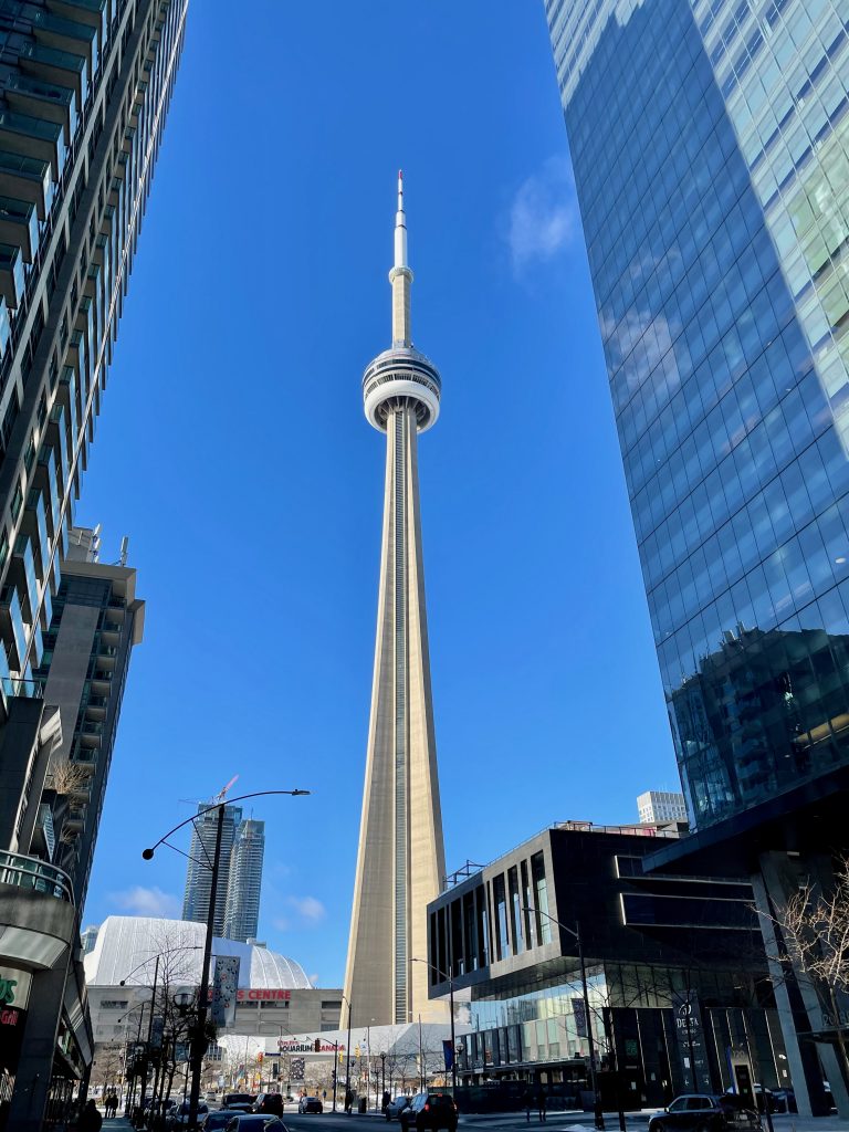 CN Tower unter blauem Himmel umrandet von Hochhäusern